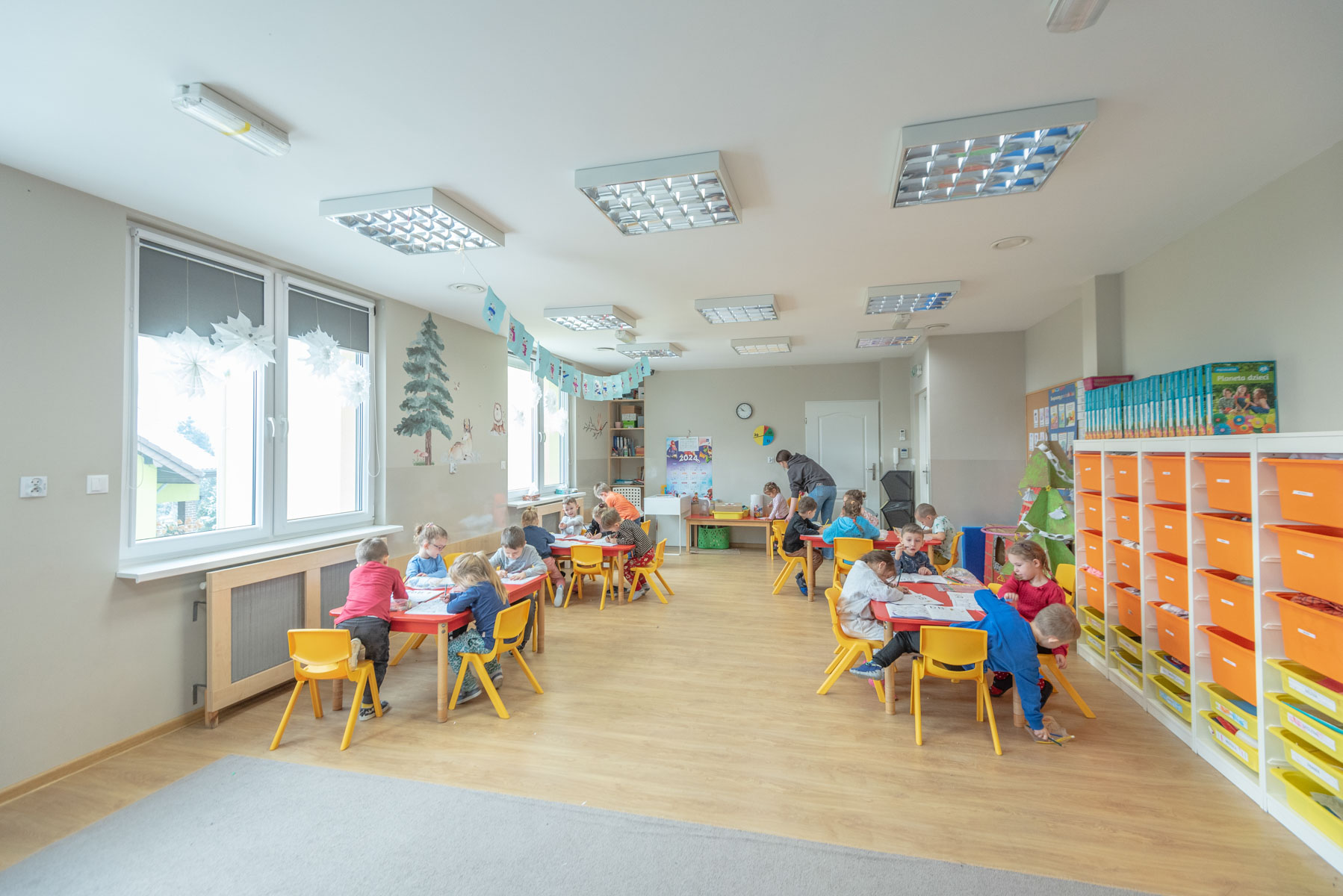 Widok sali przedszkola z bawiącymi się dziećmi