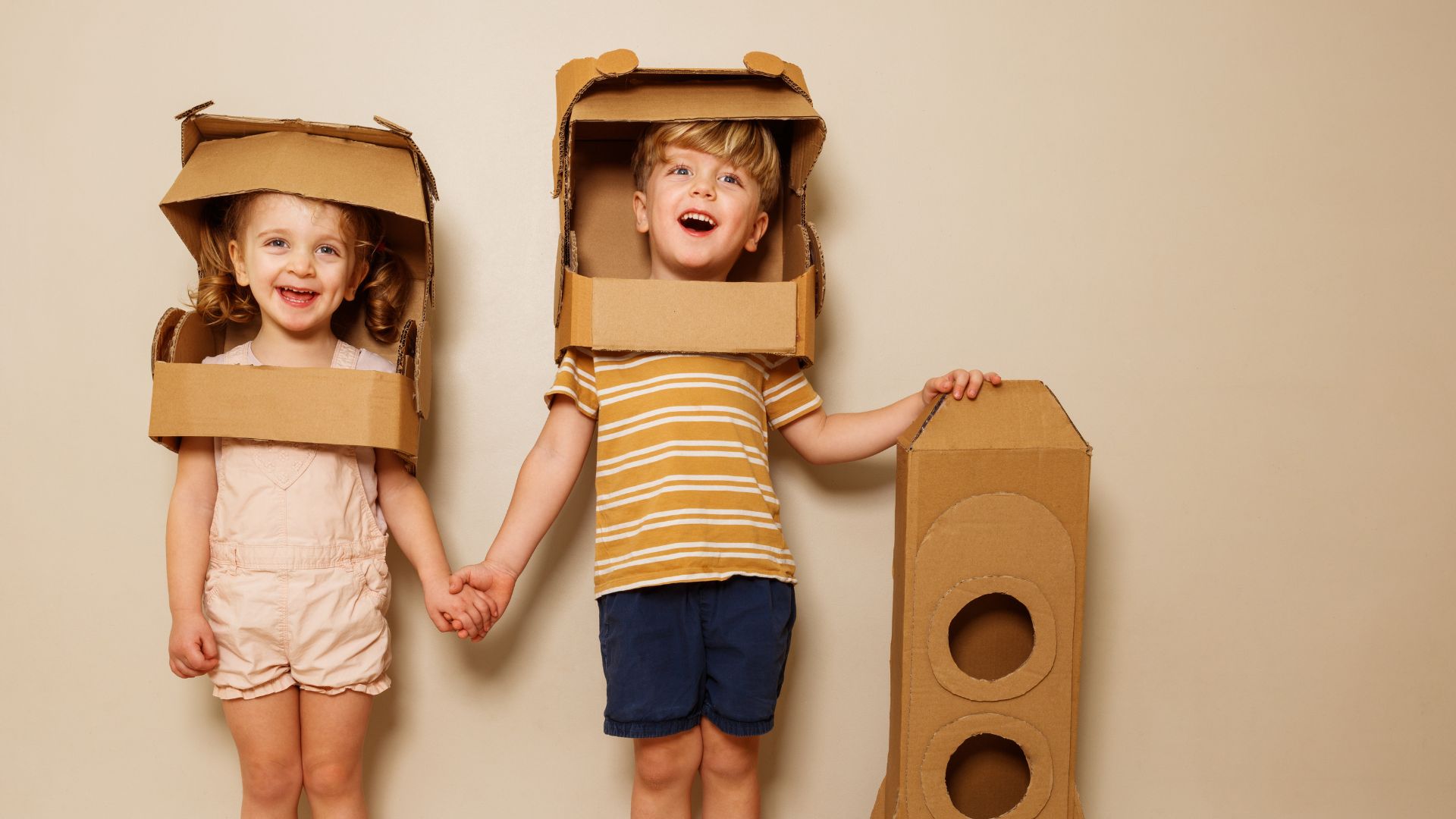 Dzieci bawiące się kartonowymi zabawkami w przedszkolu