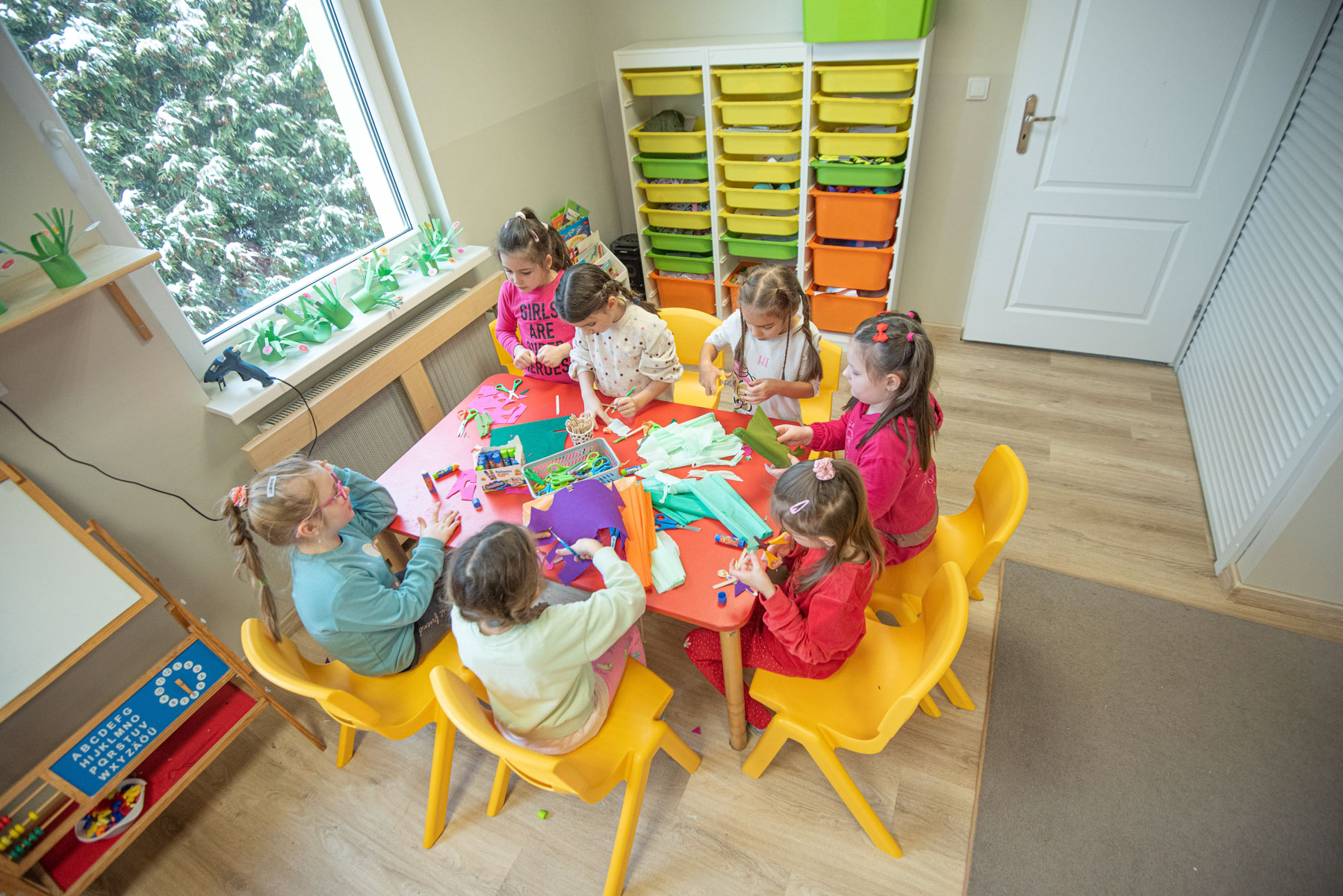 Dzieci bawią się w grupie przy stole podczas adaptacji w przedszkolu