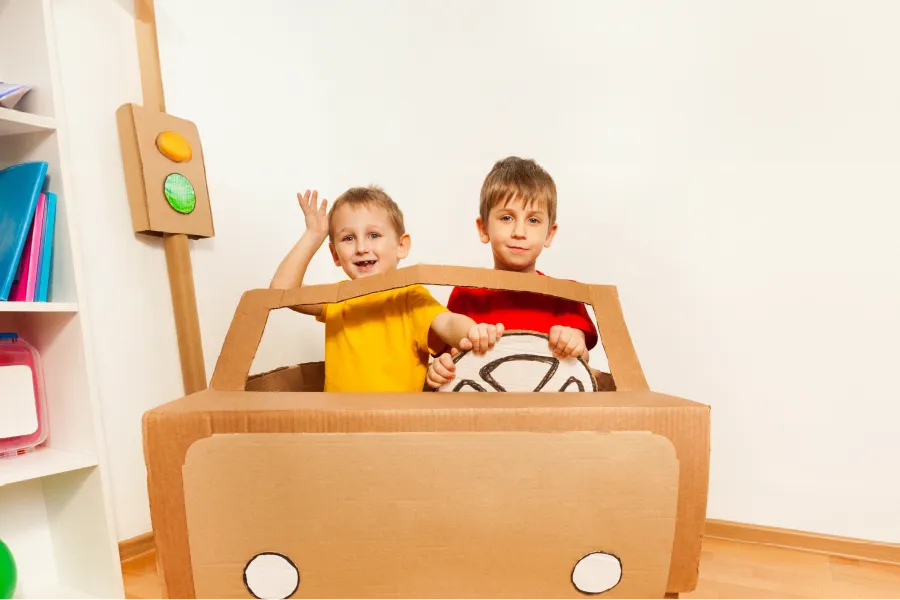Dzieci bawiące się w kartonowym aucie według plany zajęć w przedszkolu
